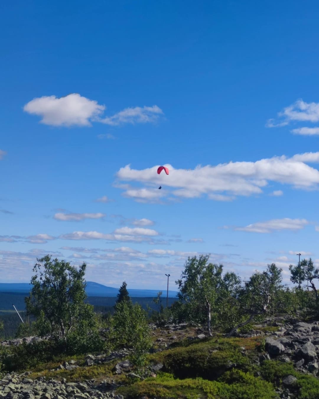 Ein Gleitschirmflieger schwebt in der Bergbrise über dem Levi-Fjäll